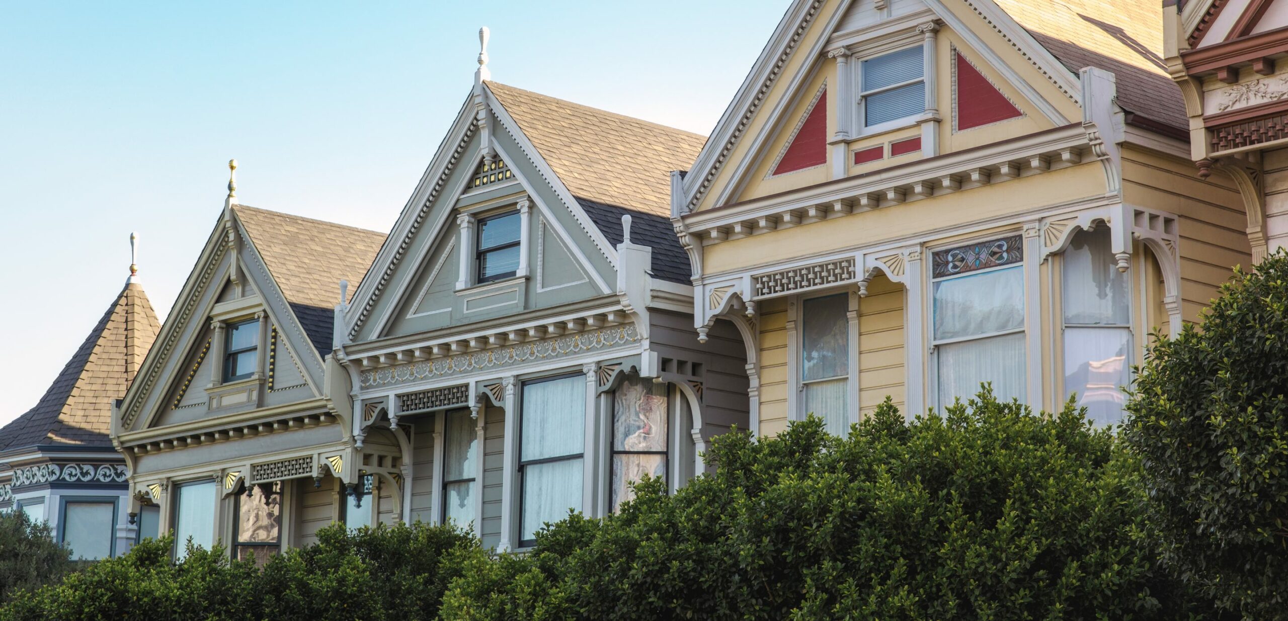 A row of painted Victorian houses at dusk