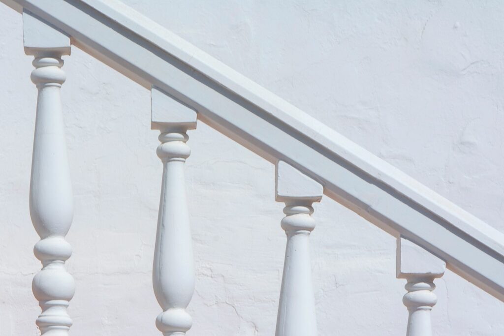 White painted stair spindles beneath a timber handrail