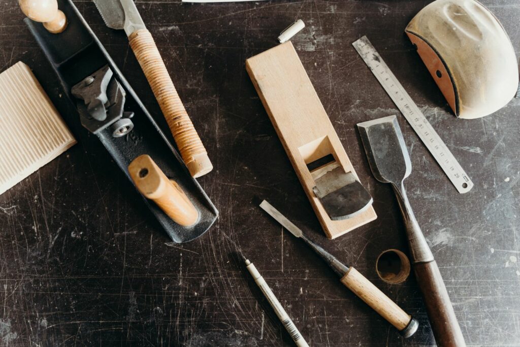 Hand tools including a plane and saw laid out on a workbench