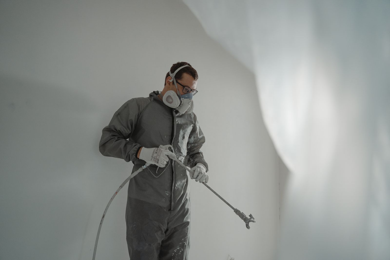 A painter in protective gear working on a wall