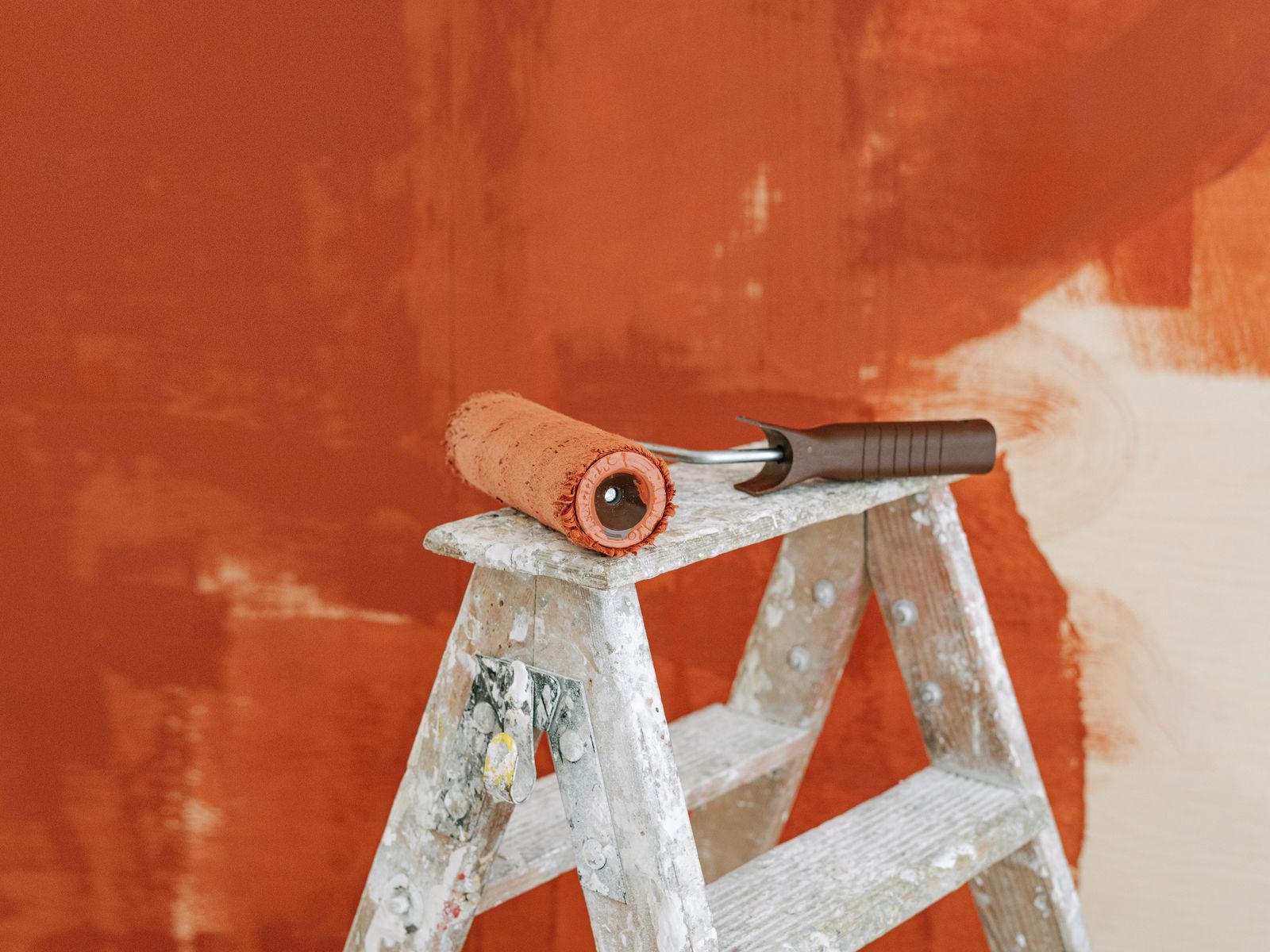 Interior painting in Woodstock, GA — a paint roller on a ladder beside a half-painted wall